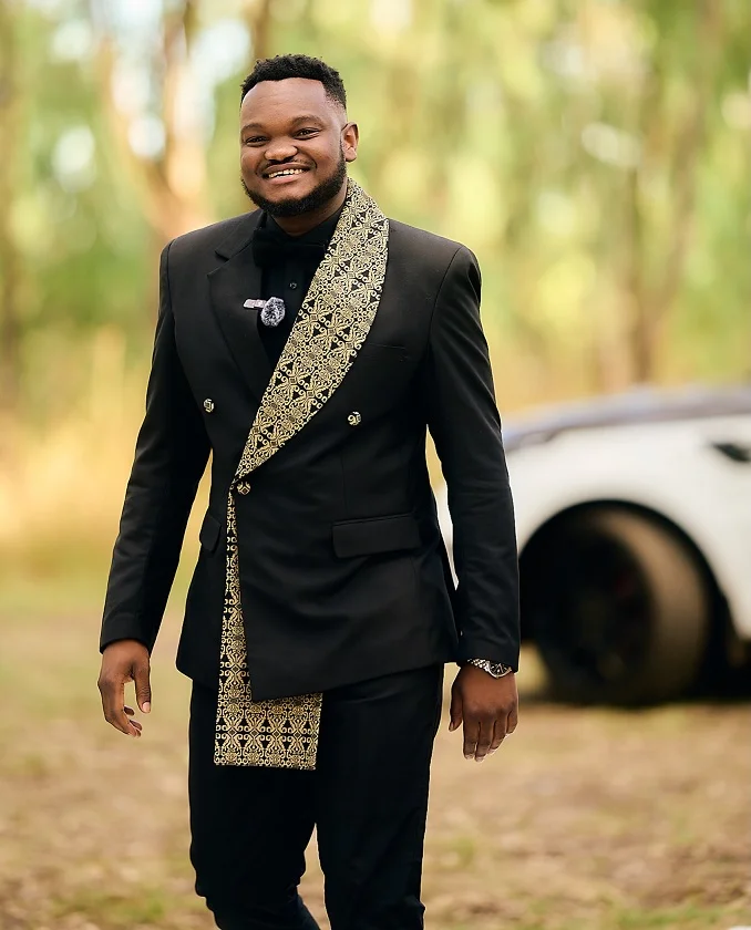 15 Plus Size Groom Outfit Ideas Trending in 2026 13 All Black Suit With a Gold Patterned Lapel Sash